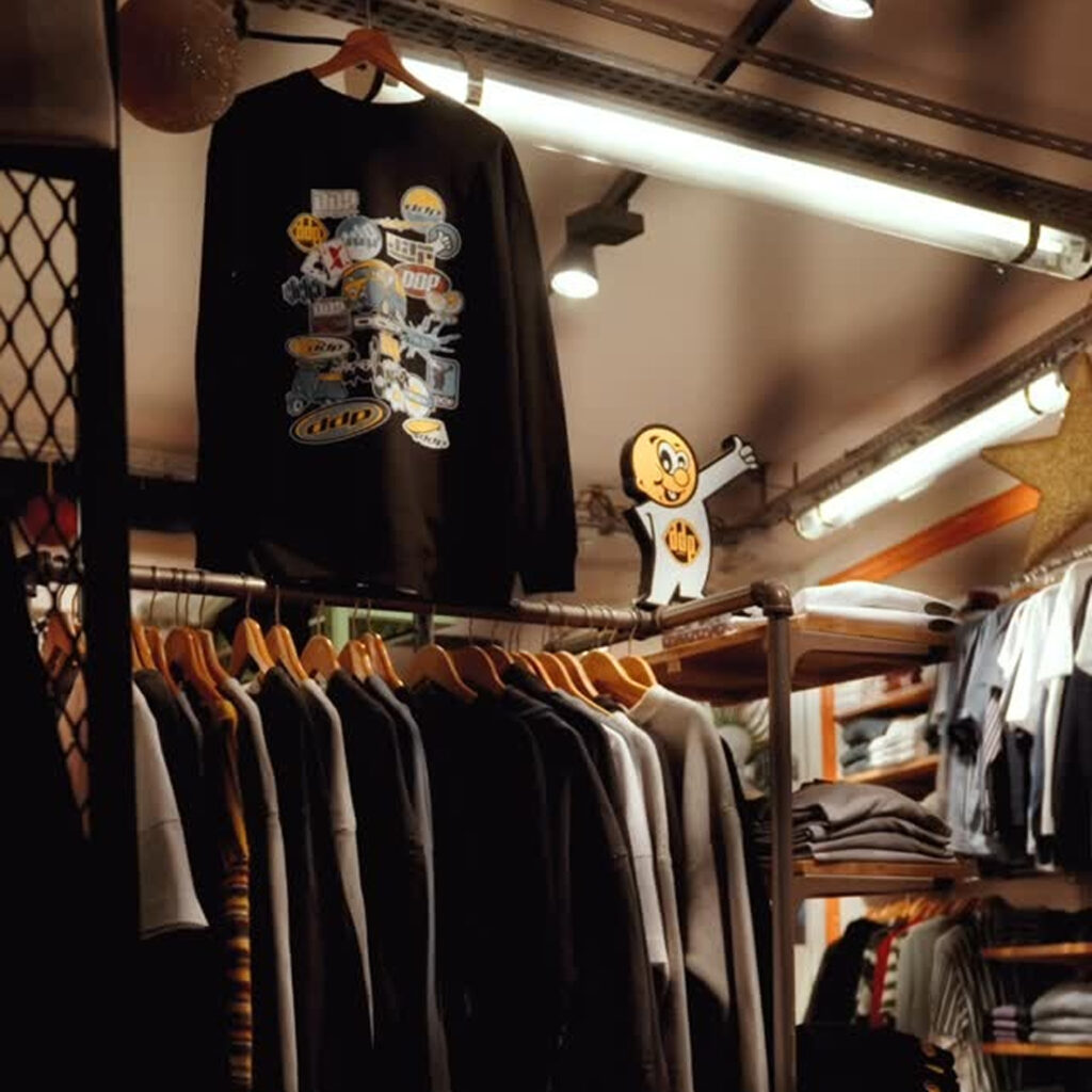 Intérieur de la boutique Kaki Crazy Station avec sélection de vêtements kaki et streetwear sur portants en bois.