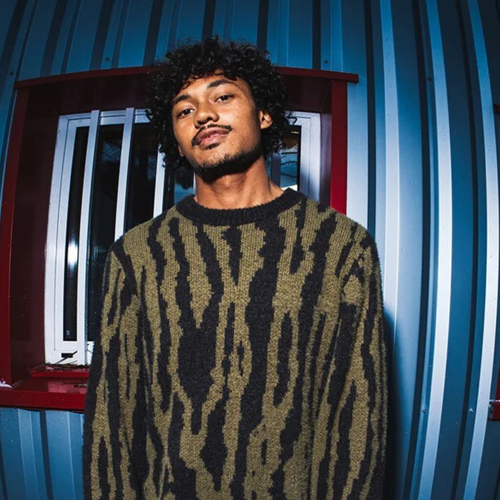 Homme portant un pull kaki à motif graphique noir, style urbain et casual, collection Kaki Crazy Station.