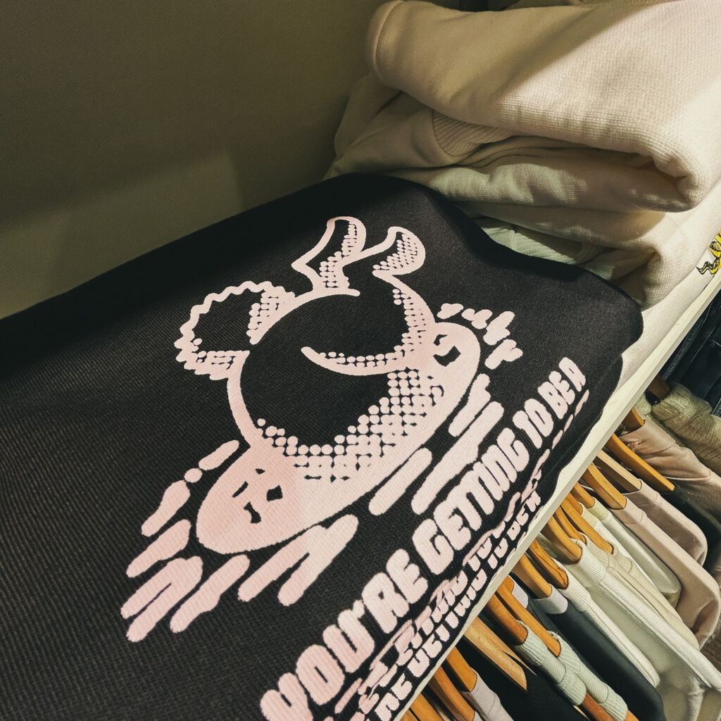 Sweat noir à motif graphique blanc, style streetwear, plié en rayon dans la boutique Kaki Crazy Station